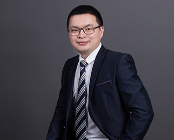 Photo of guest speaker - man smiling in suit and tie, seated