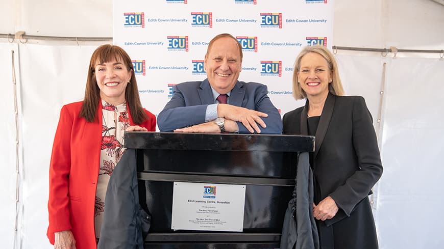 Three people standing at a lectern stand.