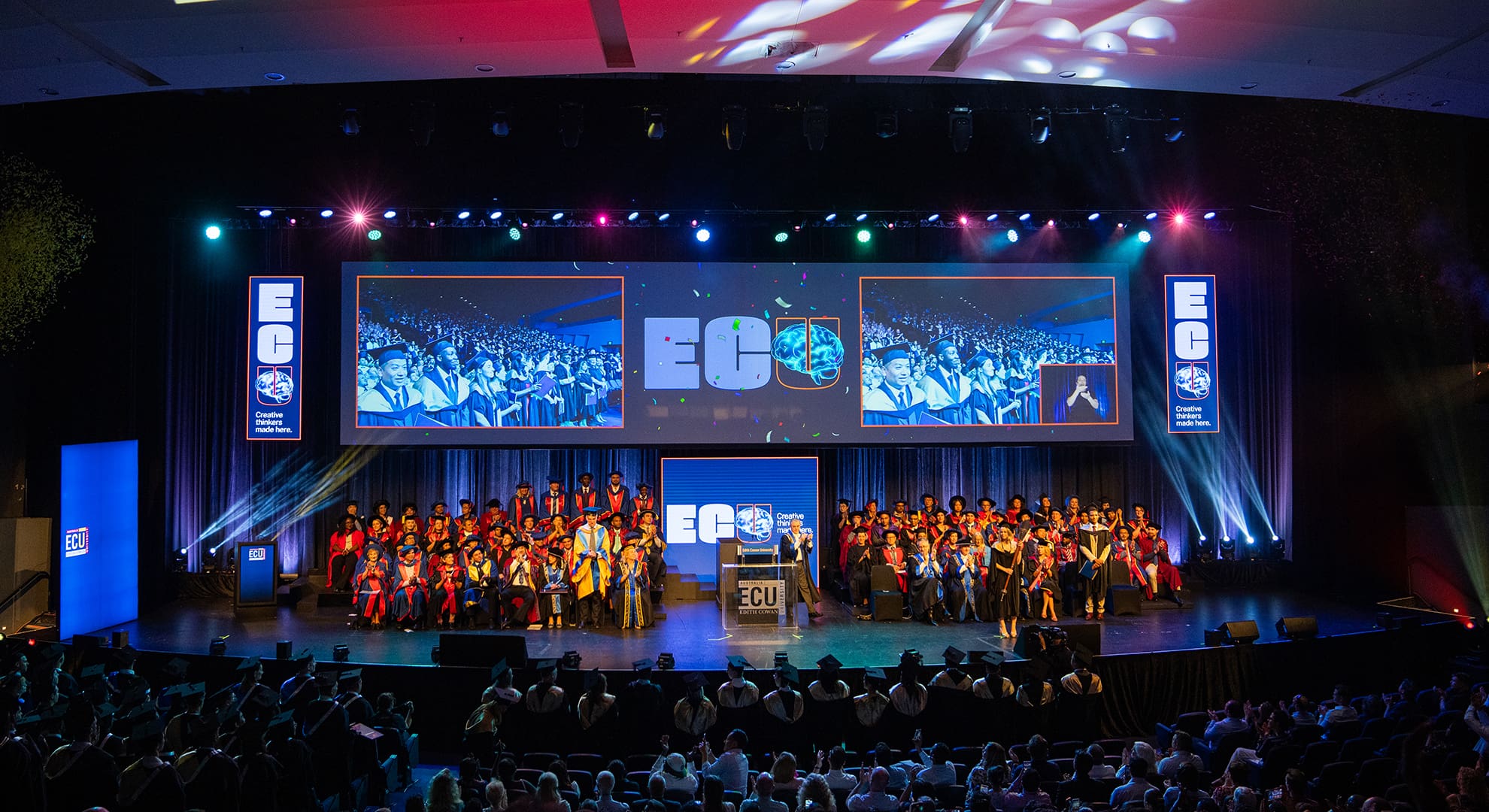 Full stage of graduation ceremony at the PCB, screens showing the audience