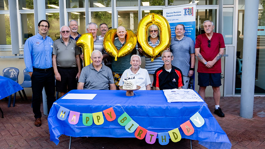 Kevin Ryan and his fellow Department of Veterans' Affairs group pose with Professor Daniel Galvao with the birthday cake.