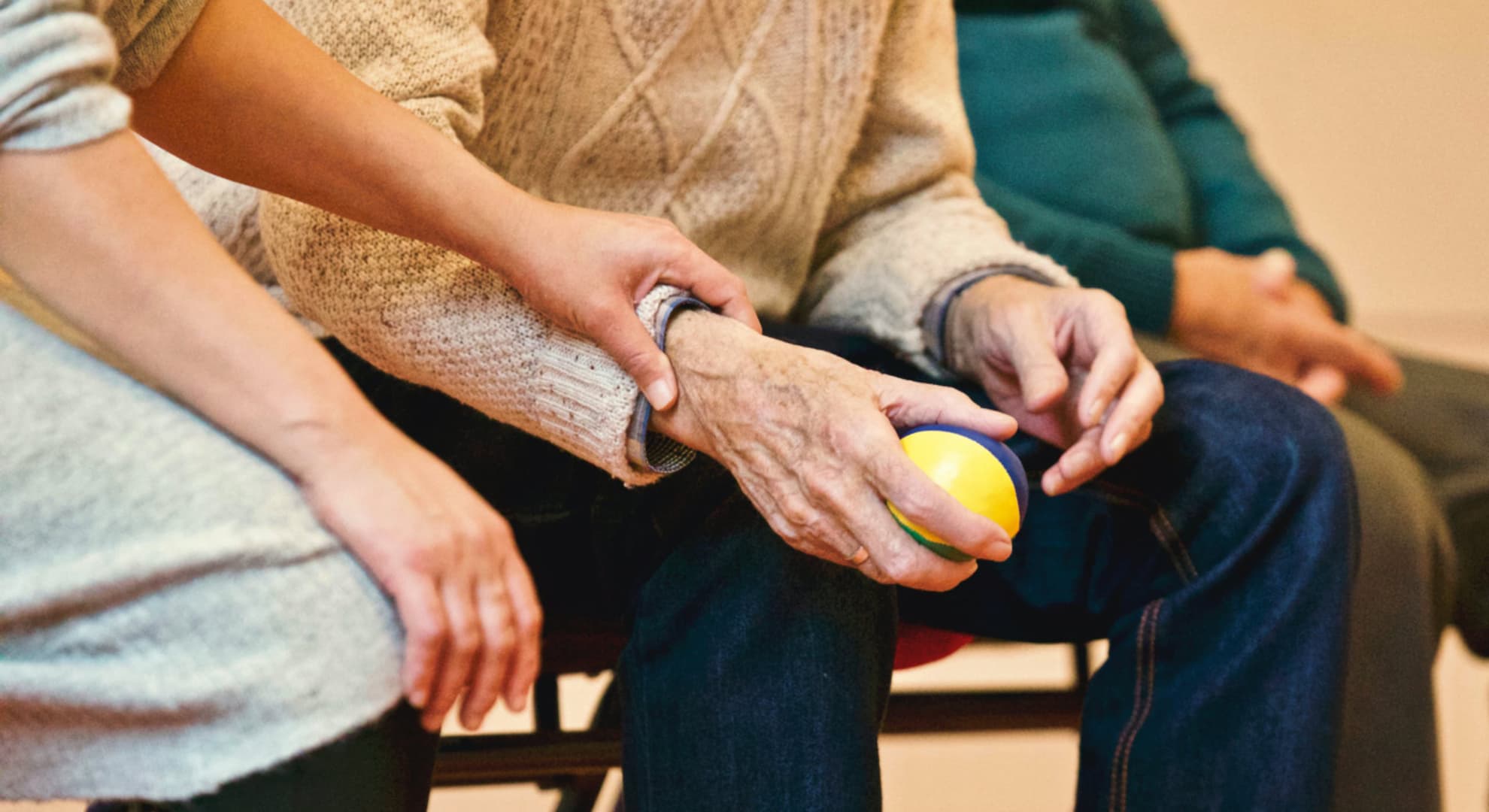 Old man holding exercise ball, sitting next to a nurse.