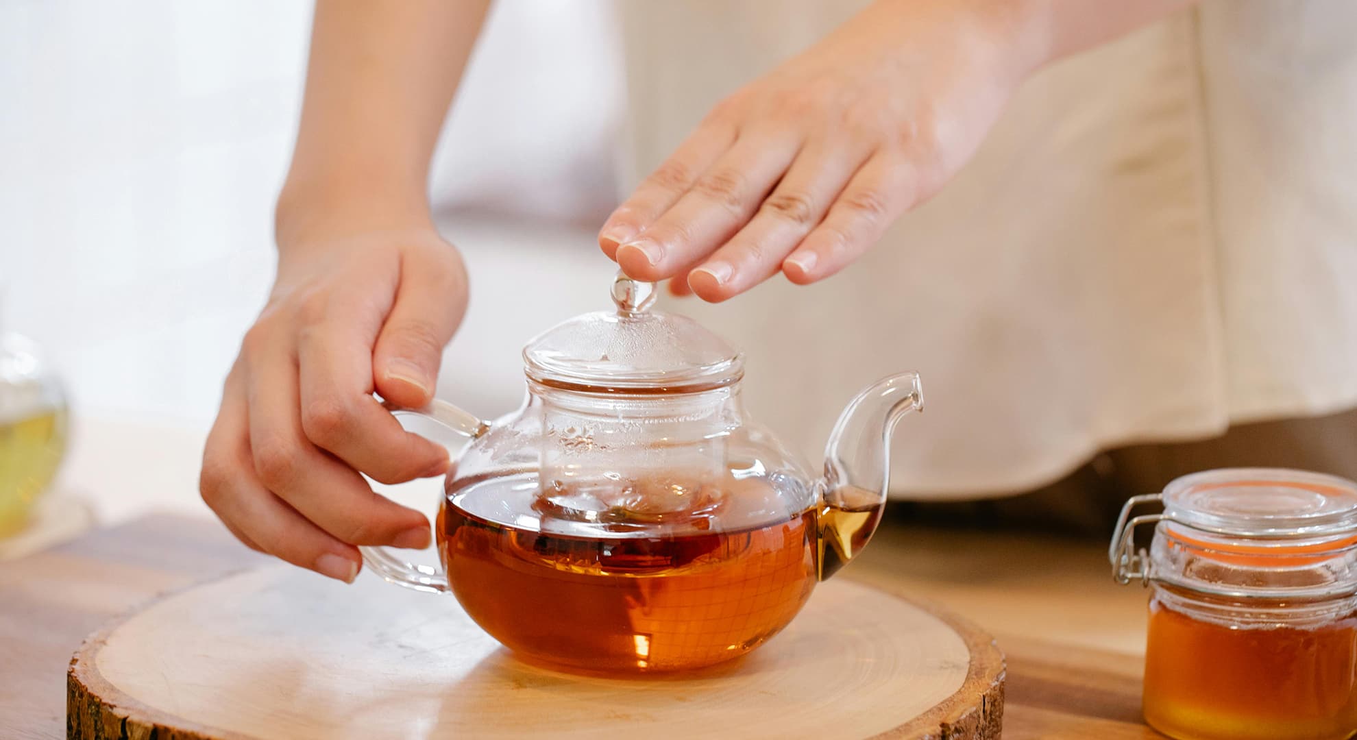 Hand holding a glass teapot with black tea.