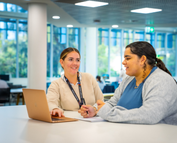 A student and a Library staff member using a laptop in the library to access Wiley e-textbooks during the platform transition from ProQuest to EBSCOhost.