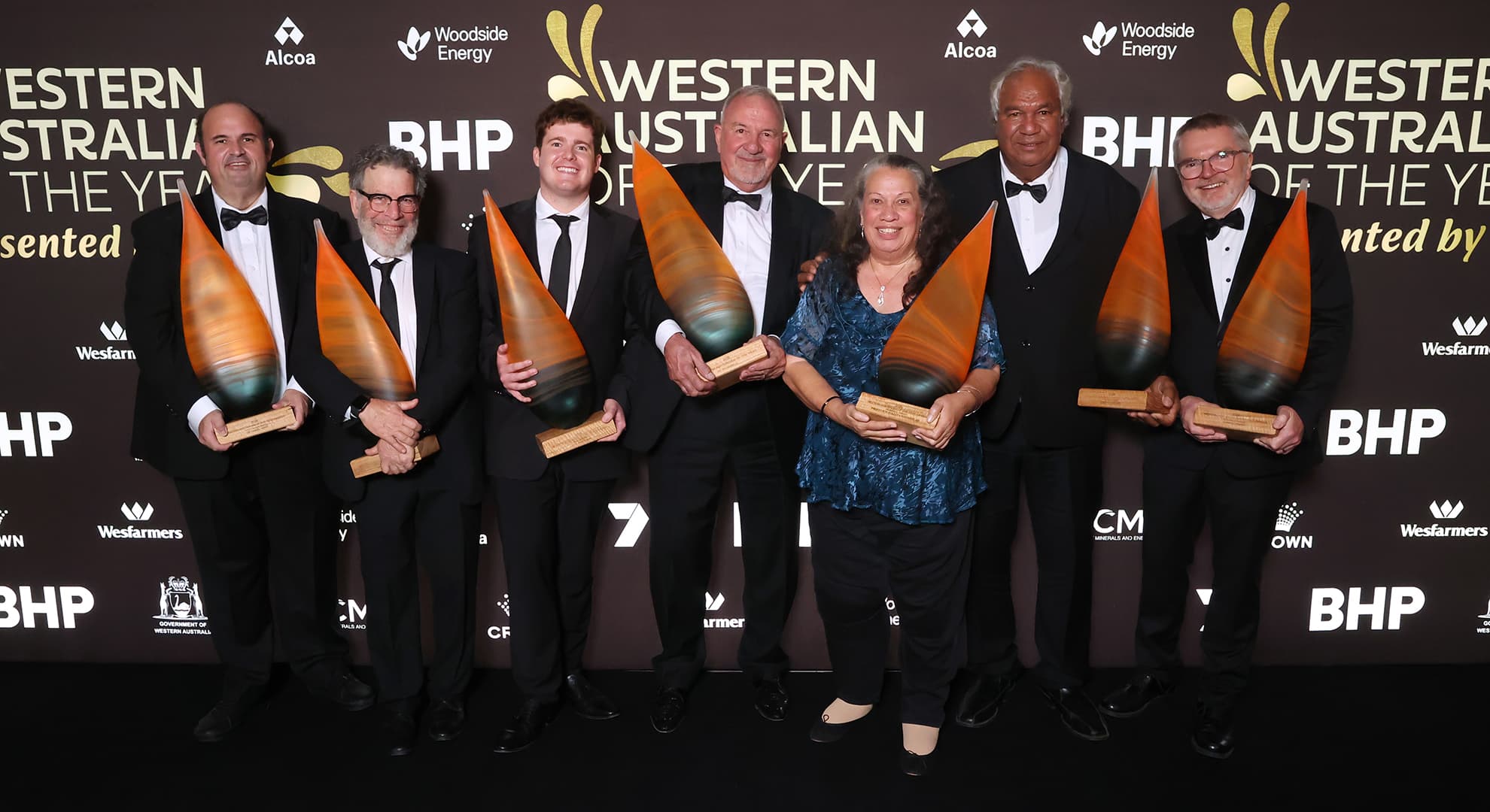 A group of individuals holding very big trophies.
