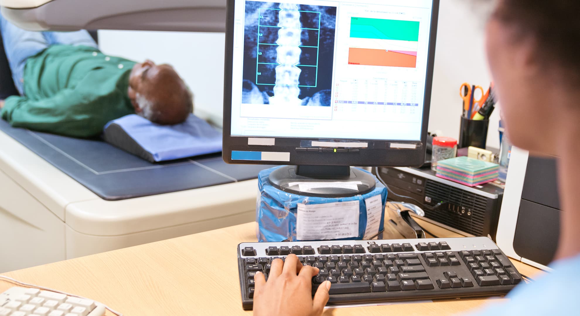 Technician looking at a screen as someone undergoes a bone density scan.