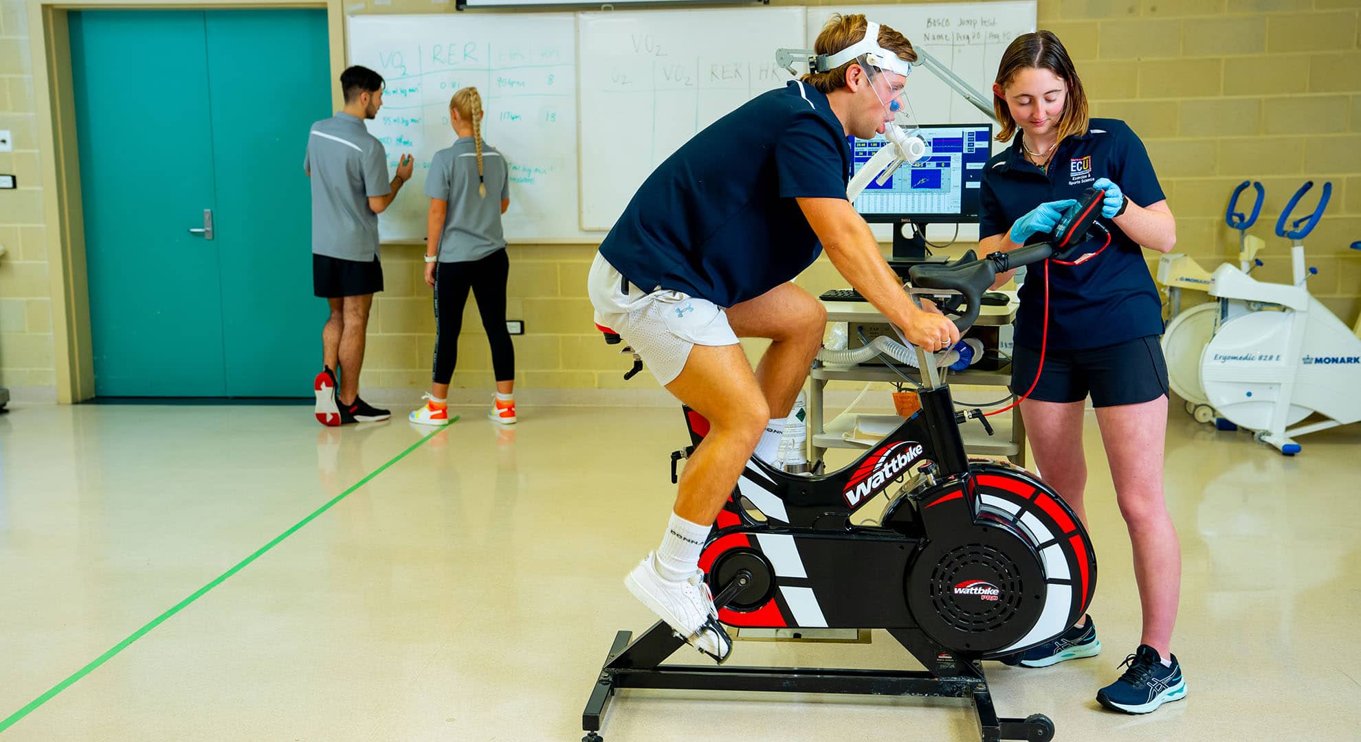 Female student in laboratory with man on exercise bike