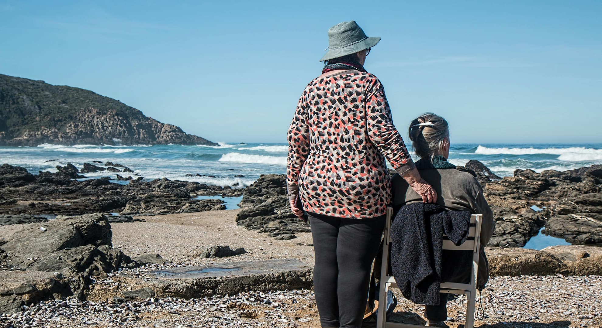 Two older women facing the ocean.