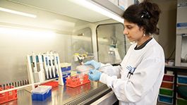 Dark haired woman holding pipette in laboratory.