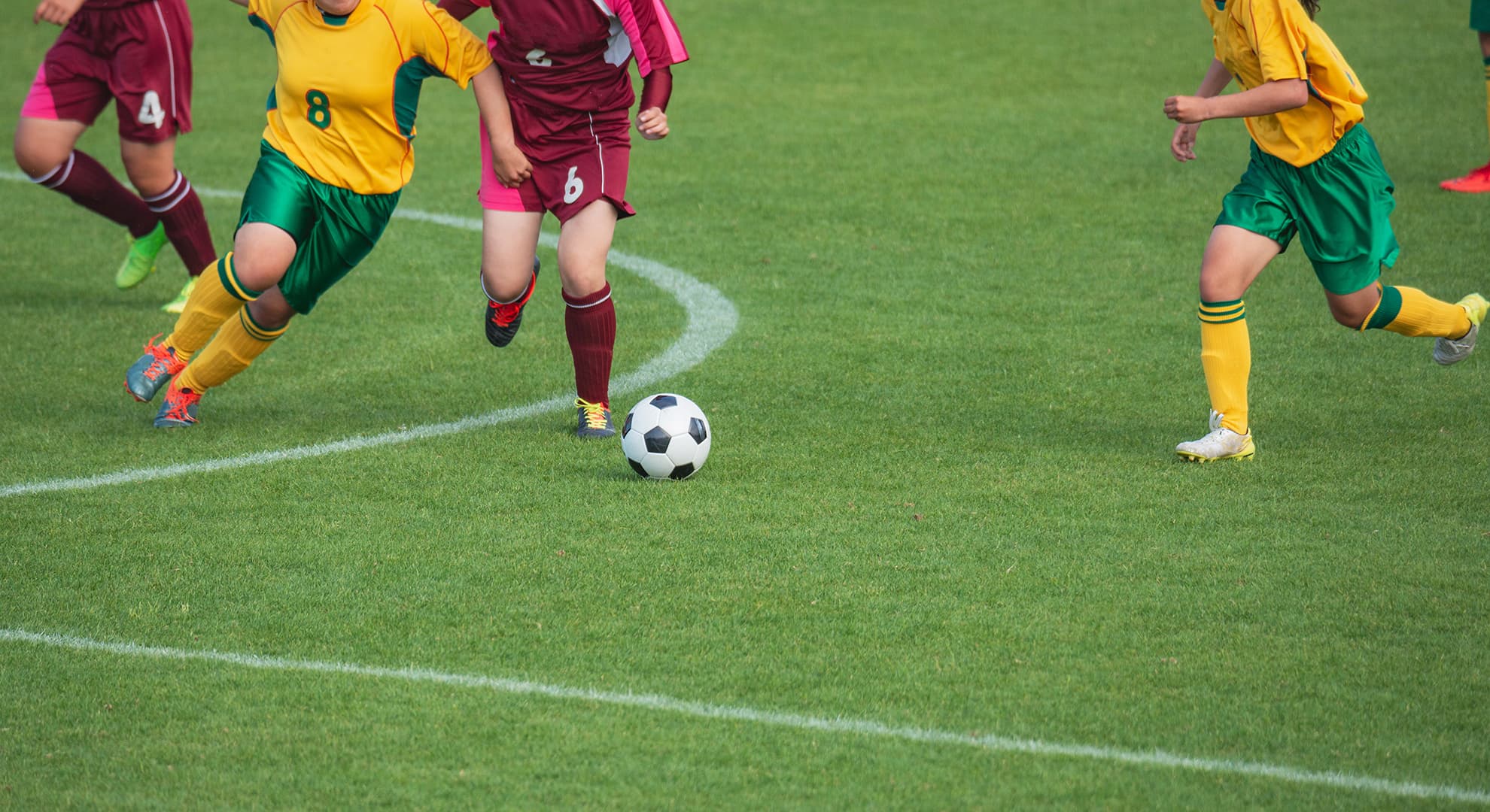 Women footballers playing a game on a green field.