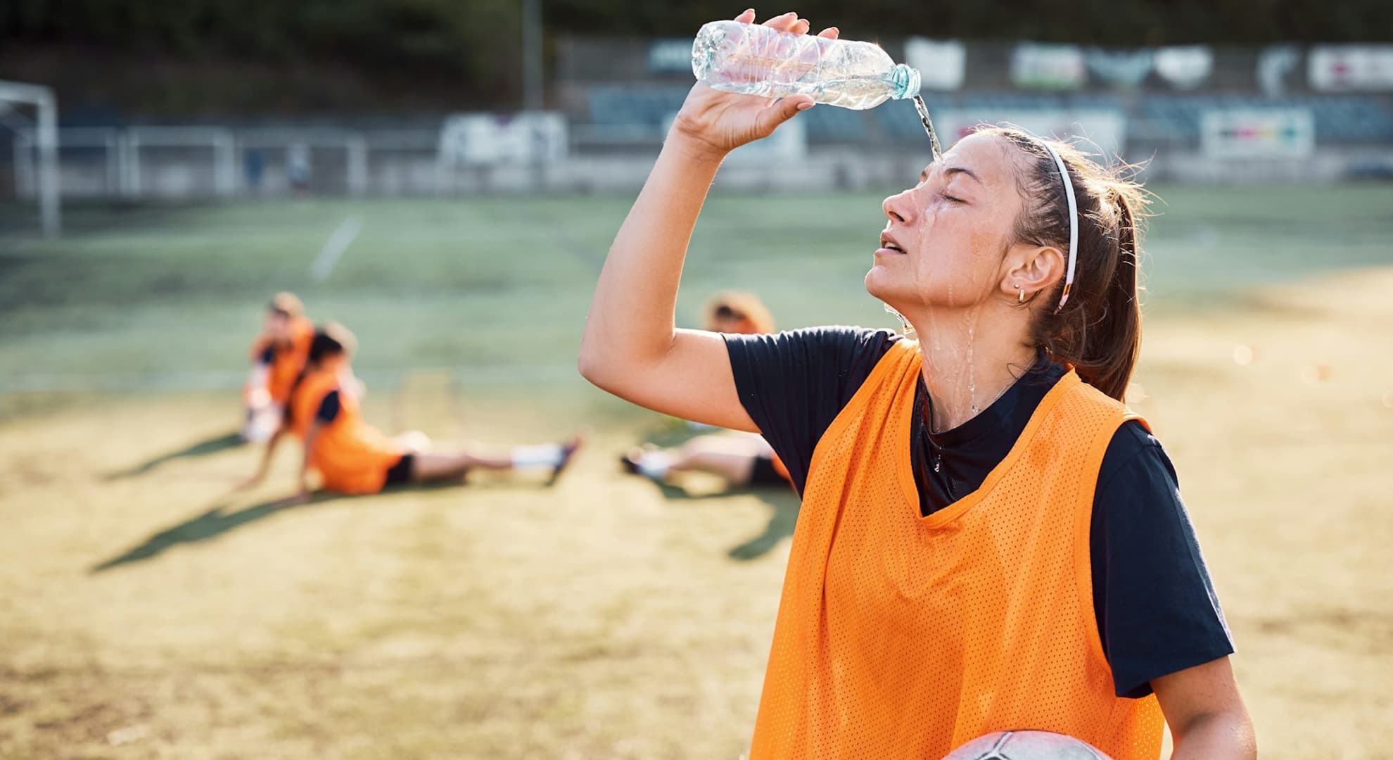 Girl with a soccer ball pouring water on her head