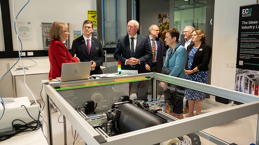 A group of people standing next to an industrial machine.