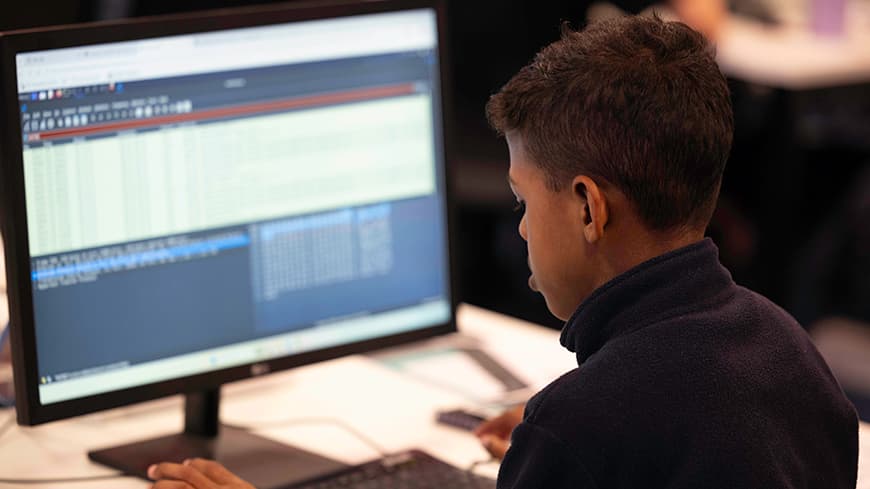 A boy sitting at a desk using a computer