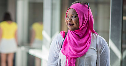 Woman wearing a pink head scarf and sunglasses on top of her head