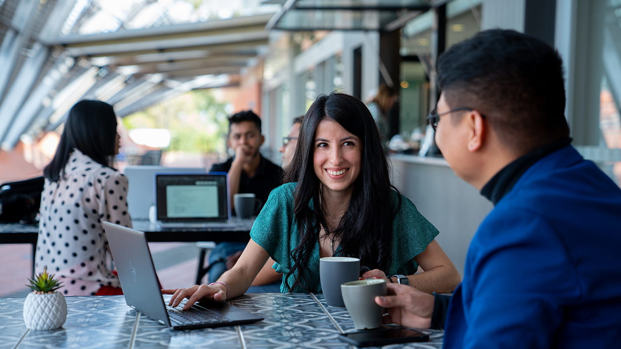 Two people at a cafe table viewing a laptop