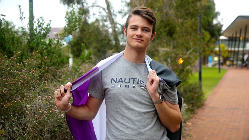Derik Grobler holds a purple, white and grey flag around his shoulders.