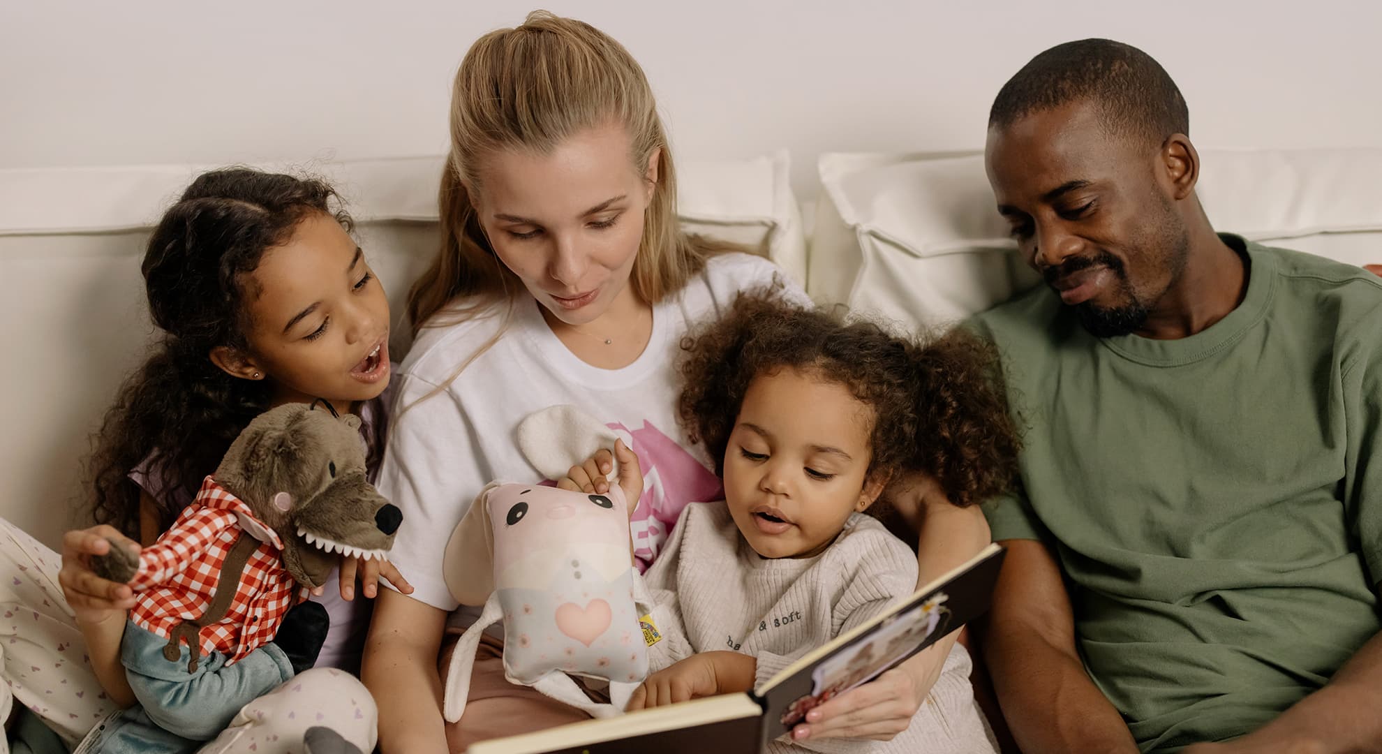 A family sits on the couch reading a picture book