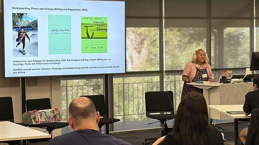 Woman standing in front of a whiteboard with skateboarding images.