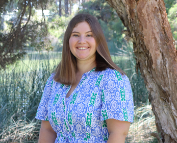 A portrait image of Dr Victoria Evans smiling standing in front of the ECU Joondalup Campus Lake.