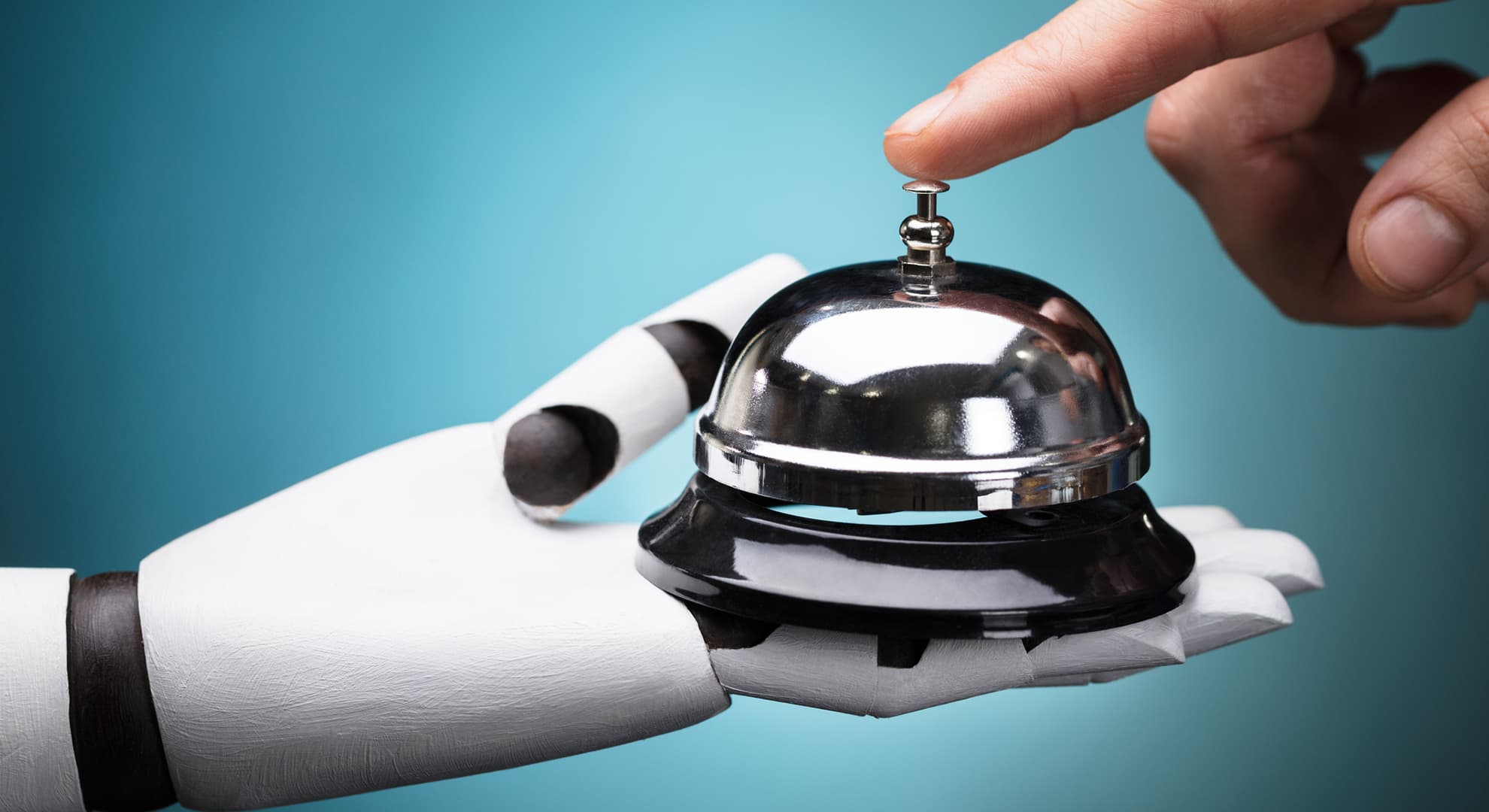 A robot hand holding a service bell, being pushed by a human hand.