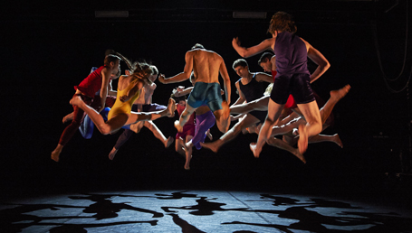 A group of people wearing bright clothing jumping in the air