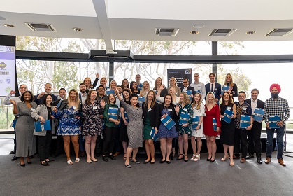 A group of people with their hands in the air, holding certificates and smiling