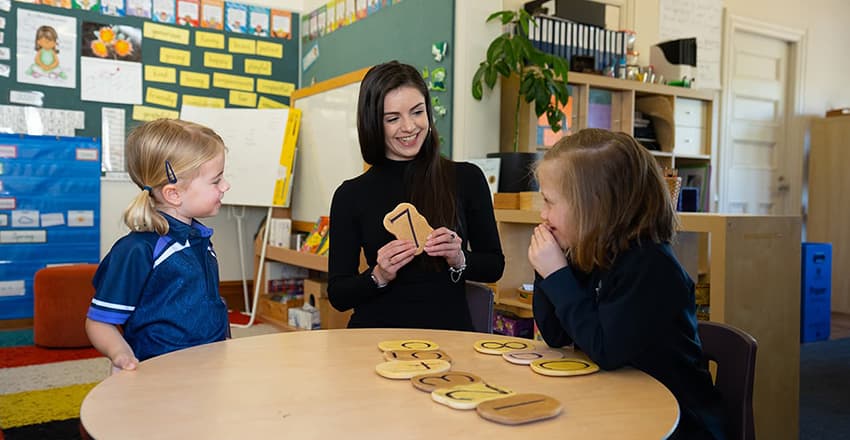 three students sitting around a desk