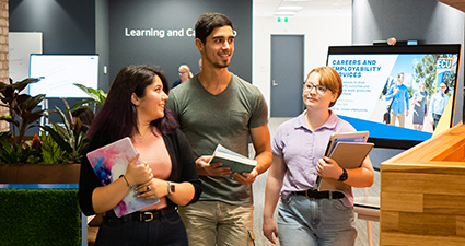 three students walking and talking in the library