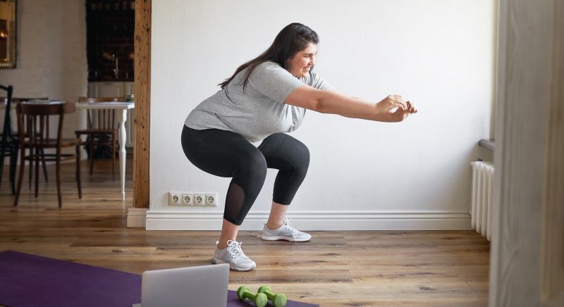 Woman performing a squat exercise in her home.