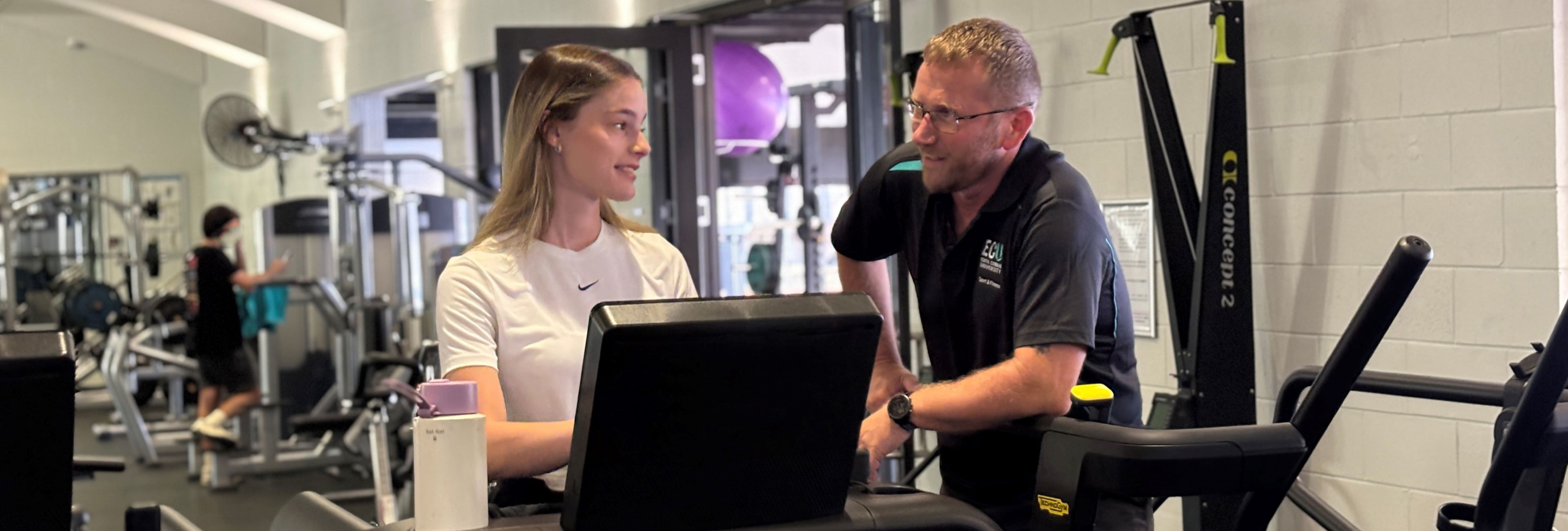 A staff personal trainer advising a gym member in the gym