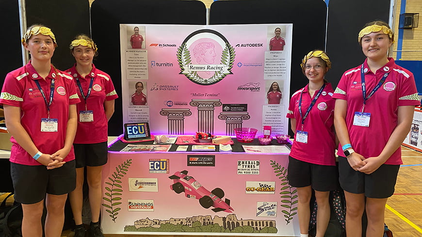 Maya, Eden Hannah and Sienna at their trade booth showcasing information about their Formula One car and project.