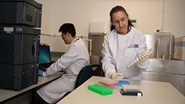 Woman in laboratory placing fluid in a test tube