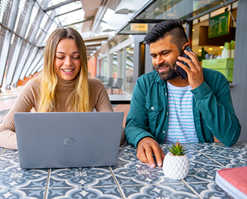 Two relaxed students seated at one of ECU Joondalup’s cafés work collaboratively on a laptop.