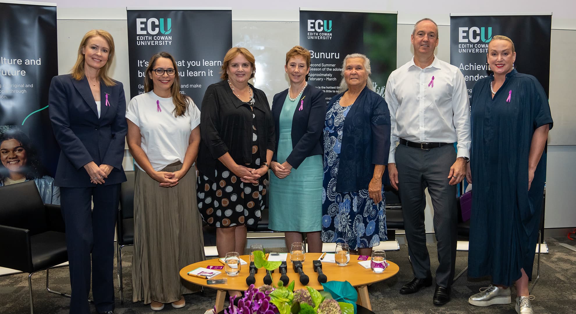 Group of nine people standing in front of ECU corporate banners.