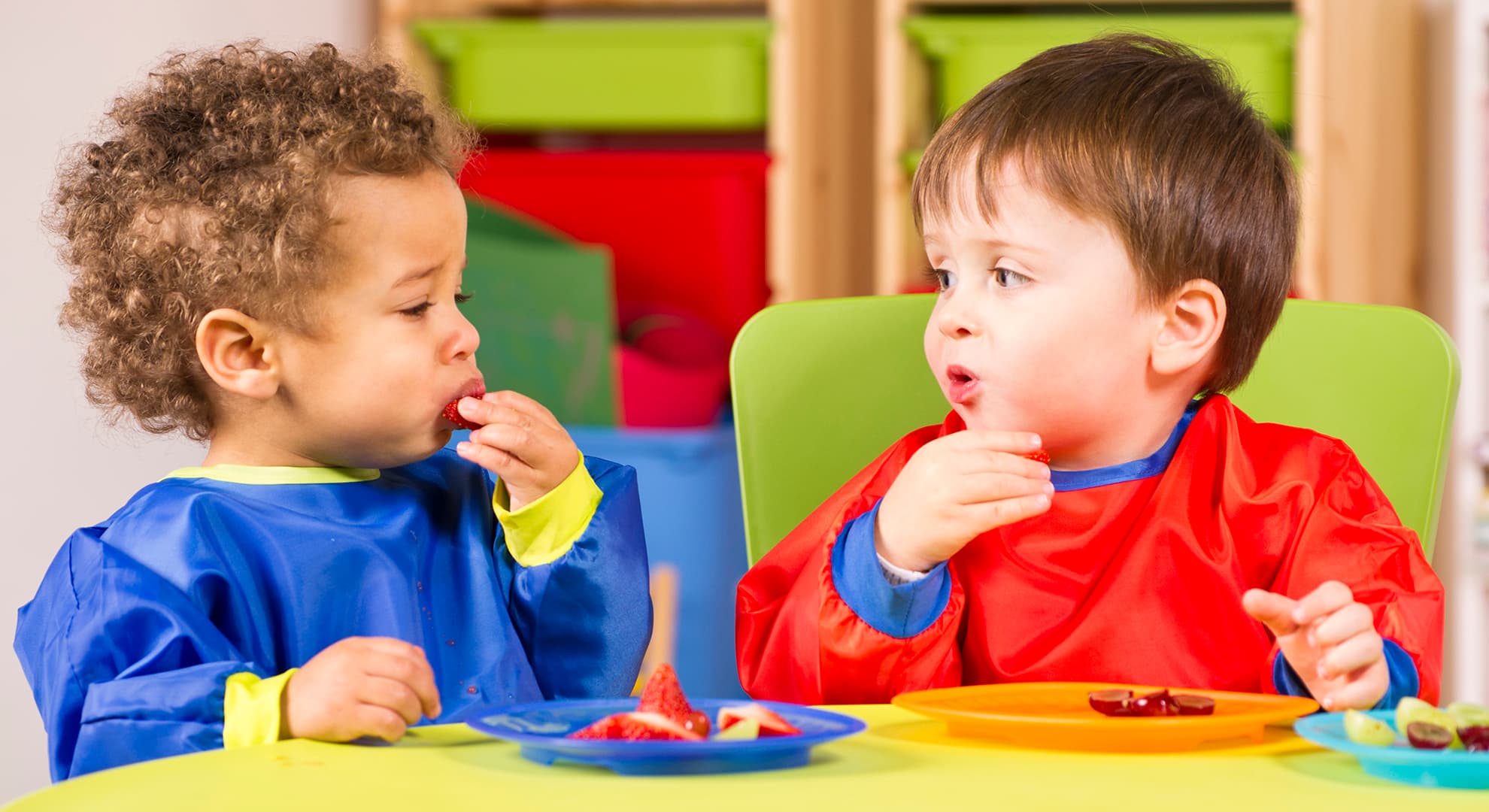 Two kindy kids eating at a table.