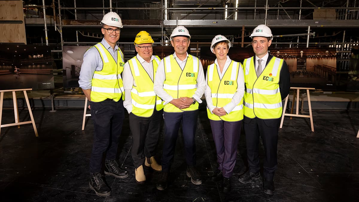 Executives standing in hard hats in front construction