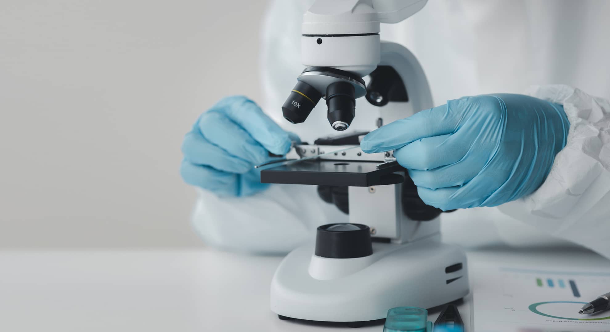 A close up of hands near a microscope.