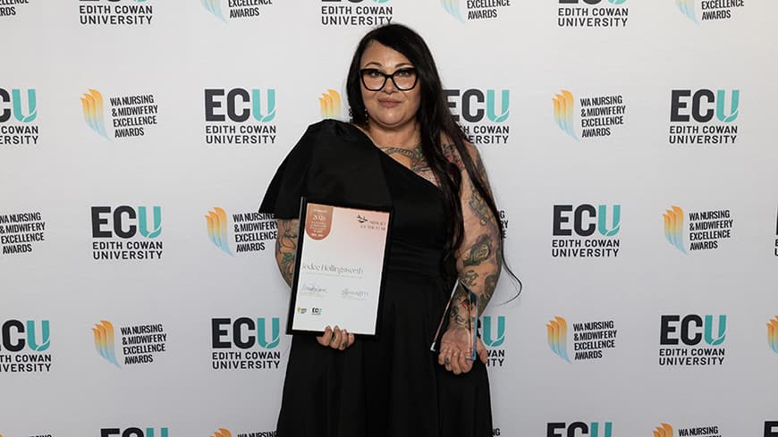 Jodee Hollingsworth facing the camera holding awards