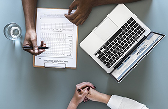 A photo of someone filling out a form and meeting with someone.