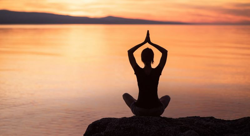 silhouette of woman in yoga pose at sunrise