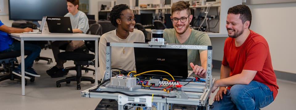 Three students programming a robot