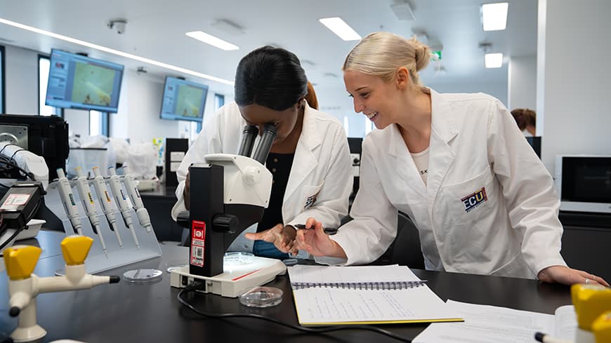Two female students working in a high-tech university laboratory.