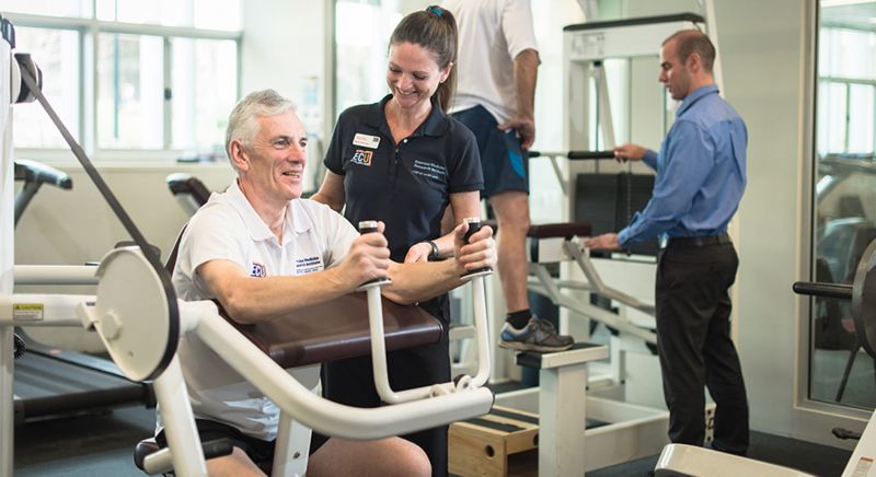 Researchers supervise older men using gym equipment.