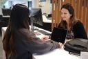 A student chats happily to a staff member as she arranges to borrow a laptop at the Library enquiry desk on level 2 at Joondalup Campus Library.