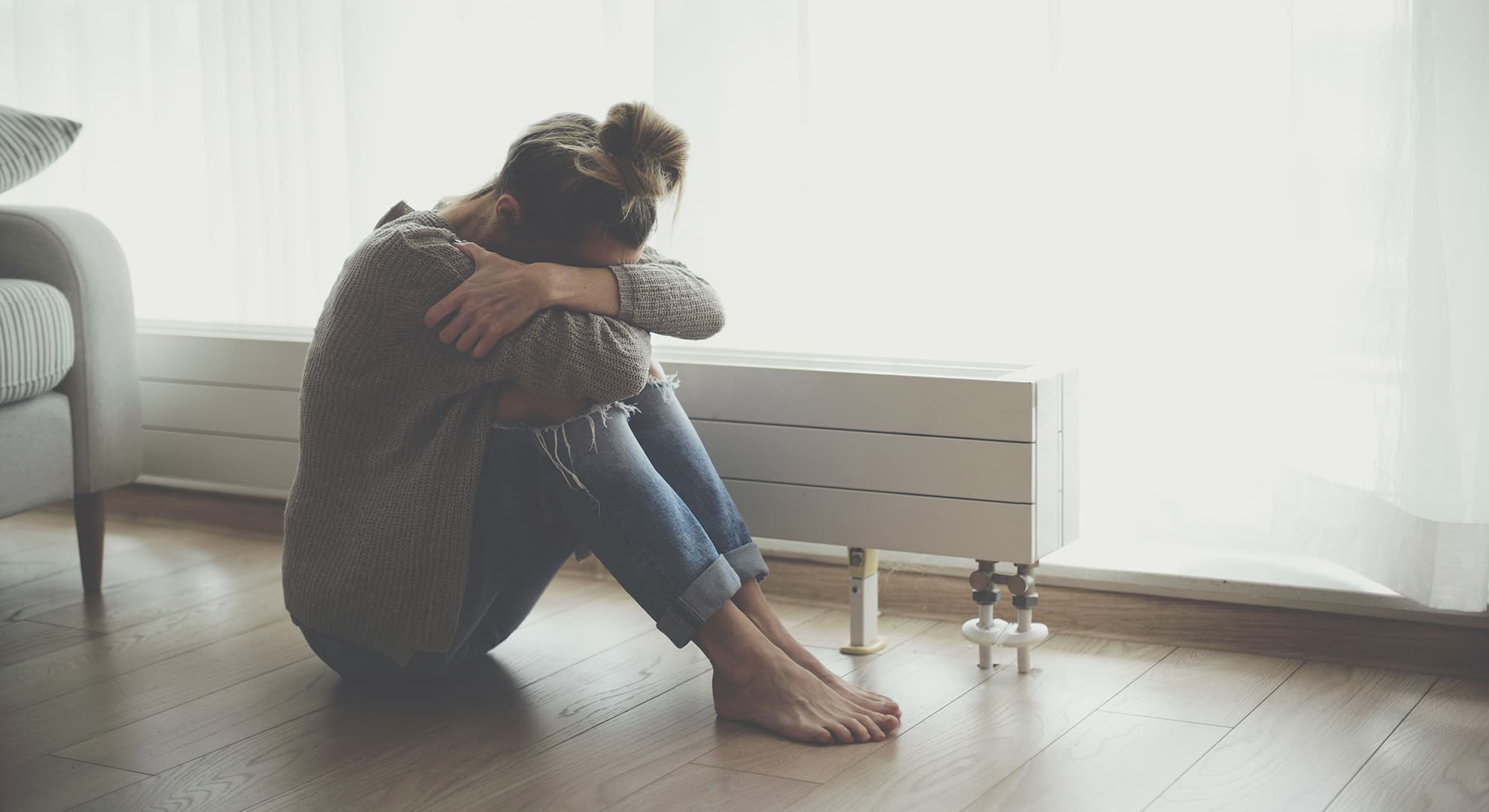 Woman sitting on the floor with face in her hands.