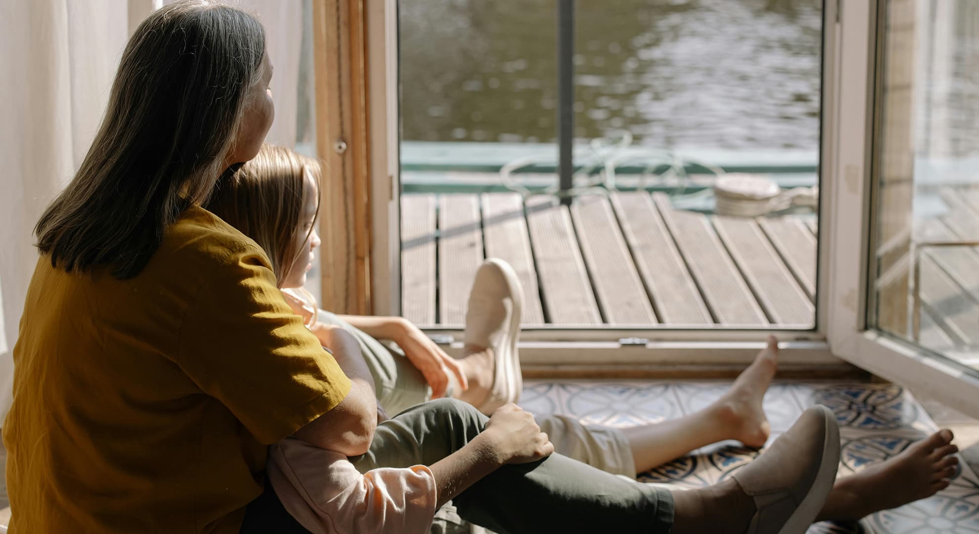 Old woman and girl sitting, facing water