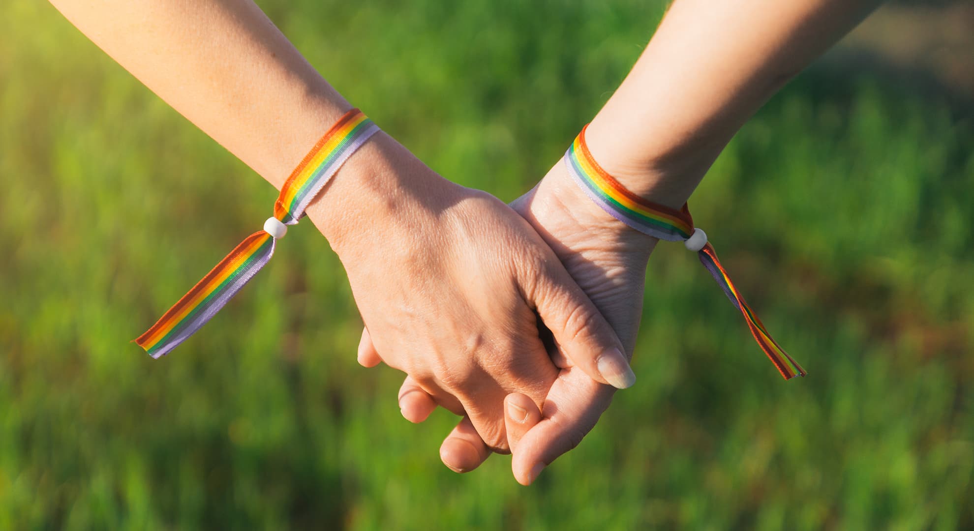 People with rainbow bracelets holding hands.