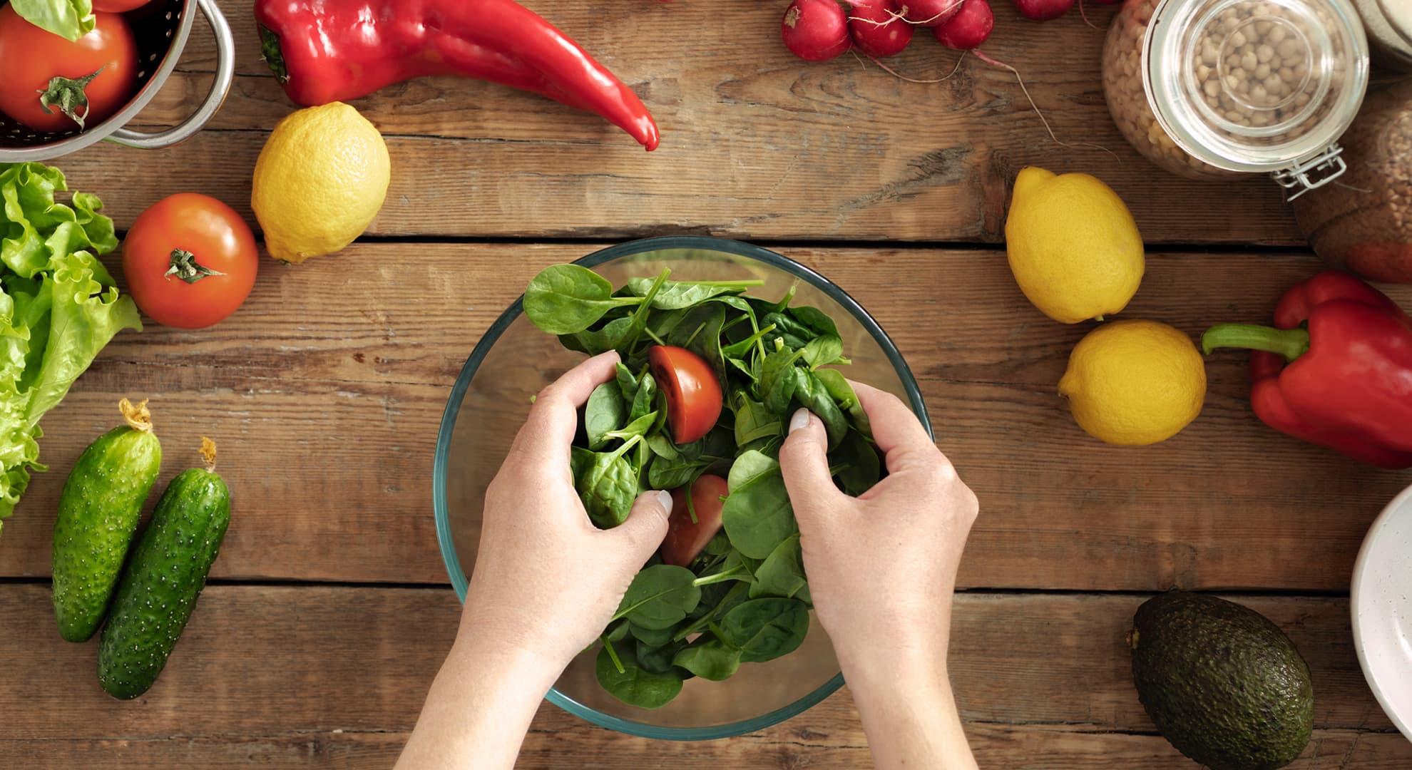 Hands preparing a green salad.