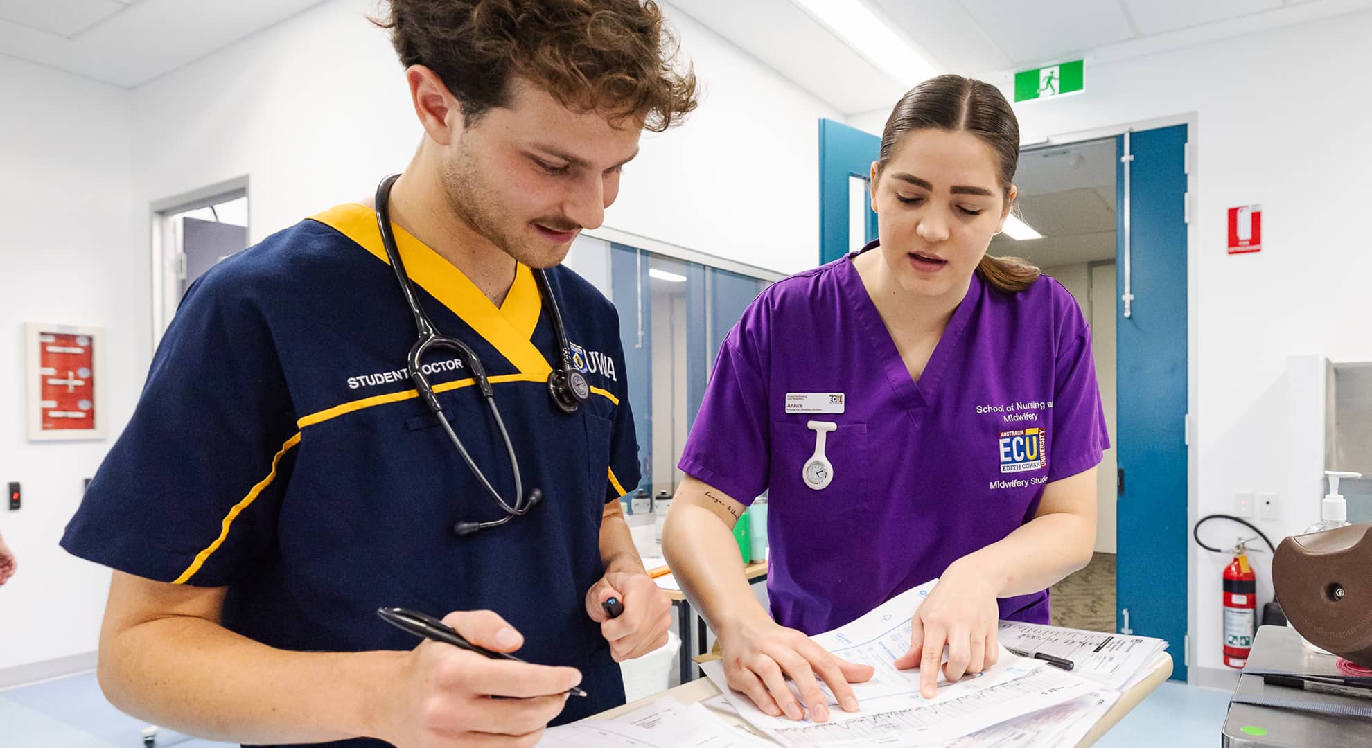 Student midwife and junior doctor looking at charts