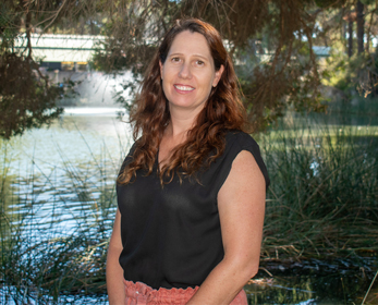 A portrait image of Mrs Julie Metcalf standing in front of the Edith Cowan University Joondalup campus lake.