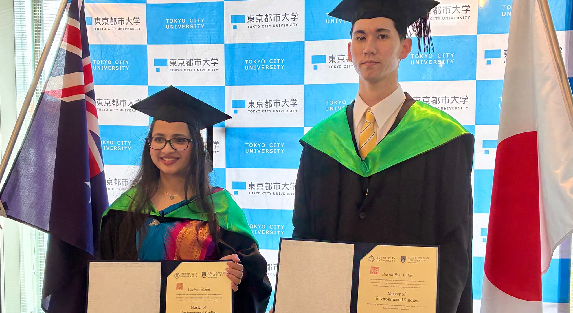 Two students holding their degrees at graduation.